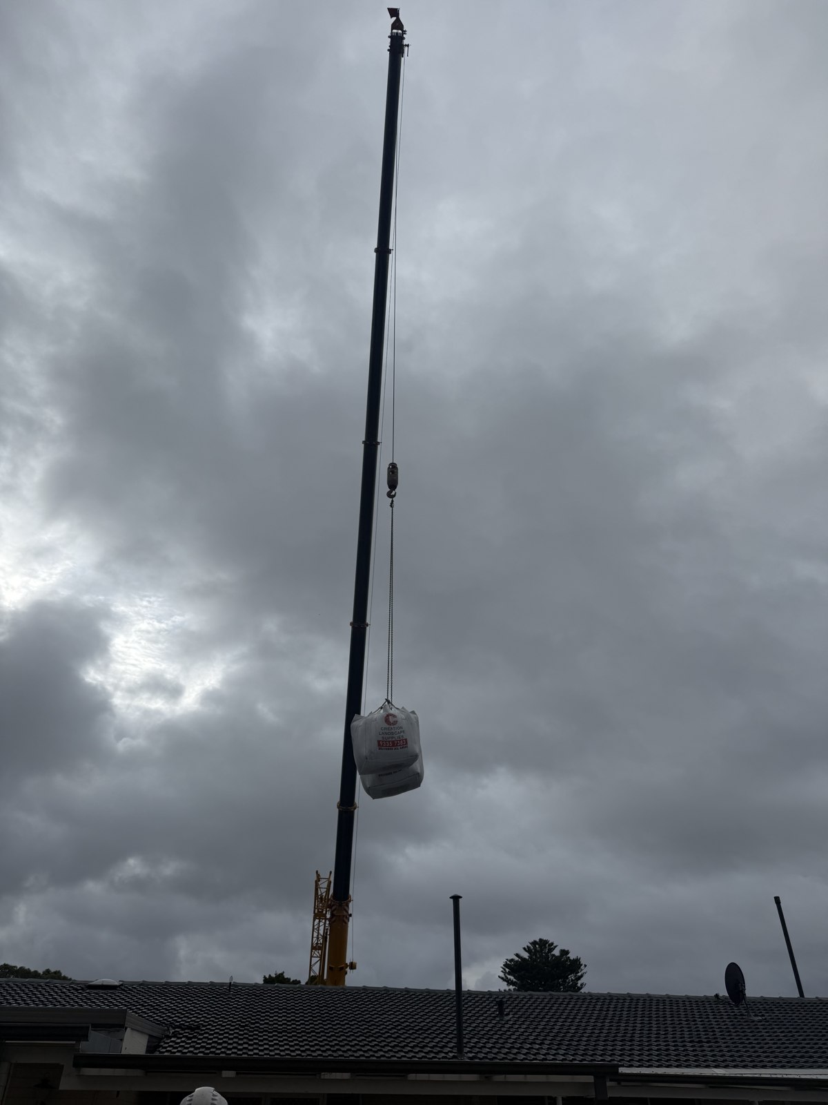 Crane lifting a bag above a residential roof