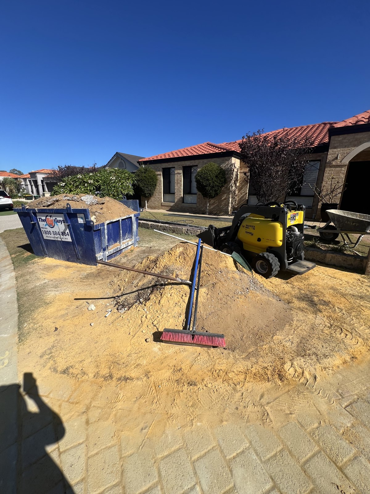 Excavated front garden with compact machinery and a skip bin