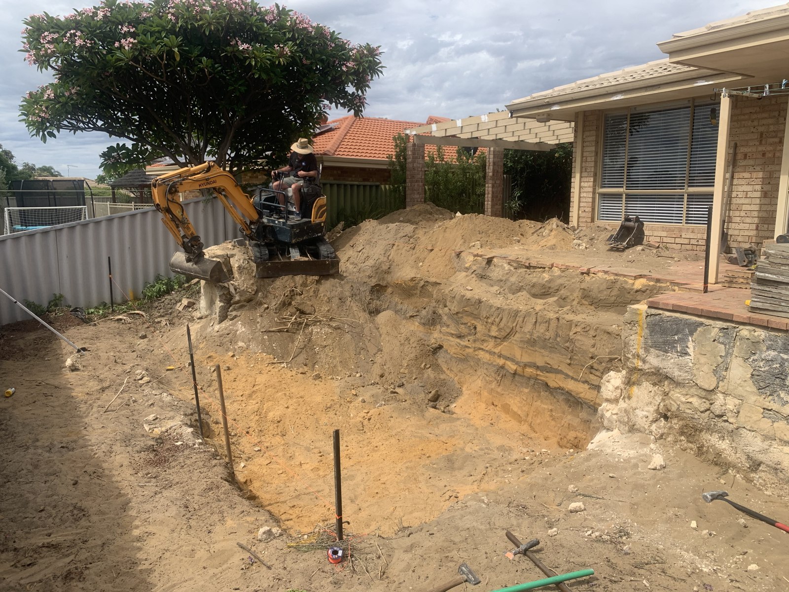 Excavator preparing ground beside a home